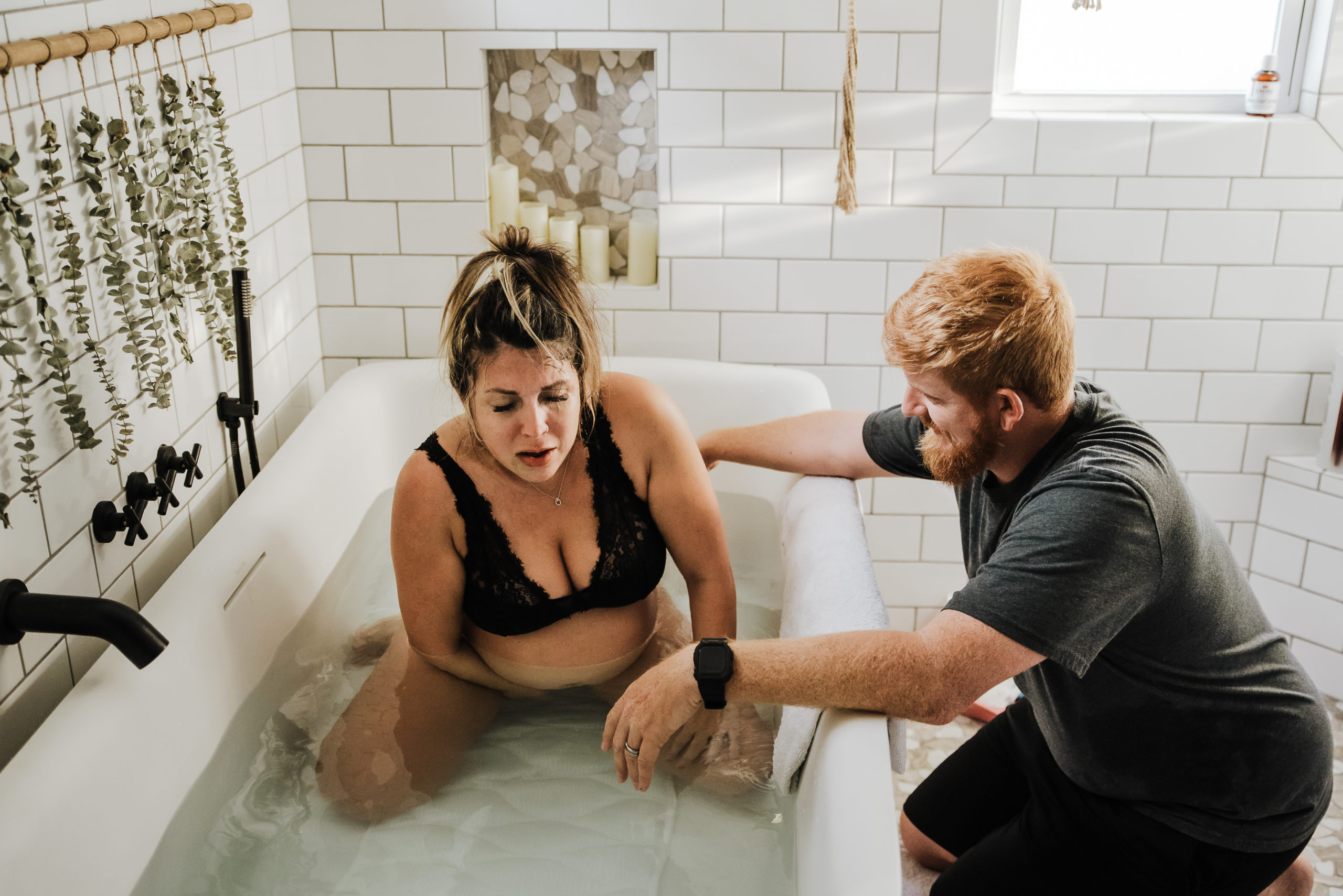 woman giving birth in tub while husband supports on the side