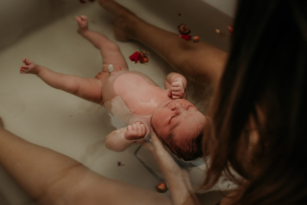 newborn in herbal bath with mom