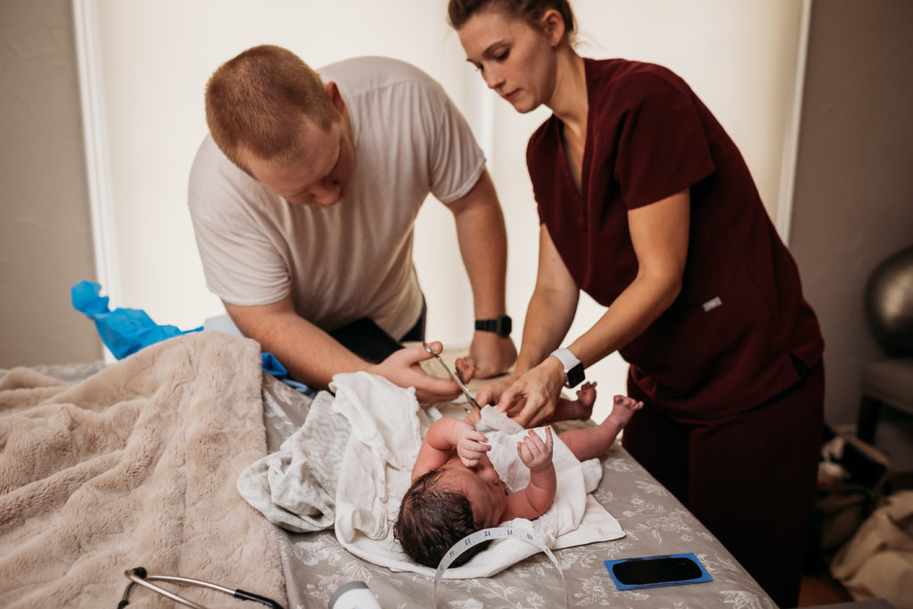 nurse assisting dad cut newborn umbilical cord