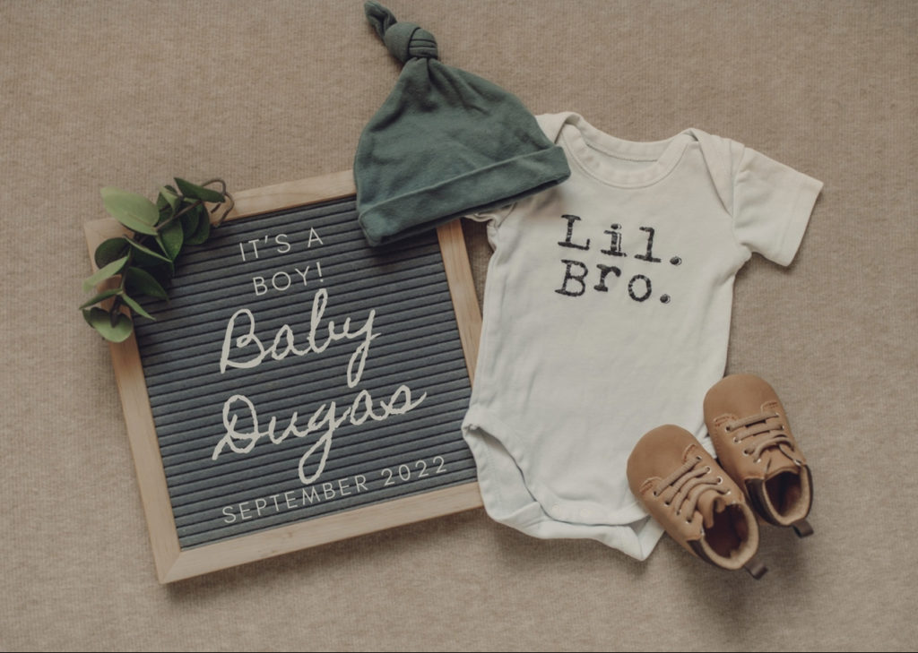 baby boy announcement on letter board with onesie, hat and baby shoes